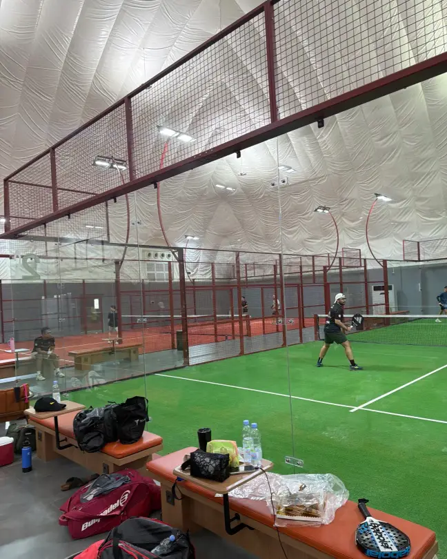 A player serving on a green padel court